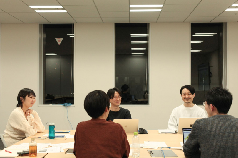 ウェブサイトの改修について話す萩原さんと、笑顔で相槌をうつプロジェクトメンバー